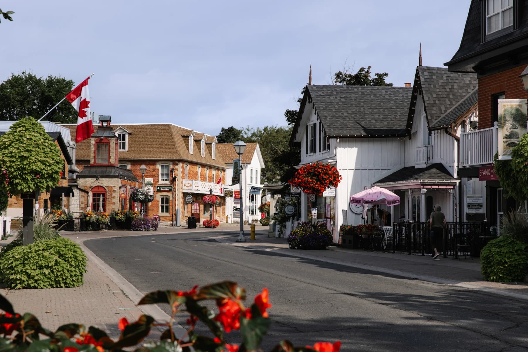 Heritage storefronts, flower baskets and a Canadian flag along historic Main Street Unionville in Markham on a summer morning