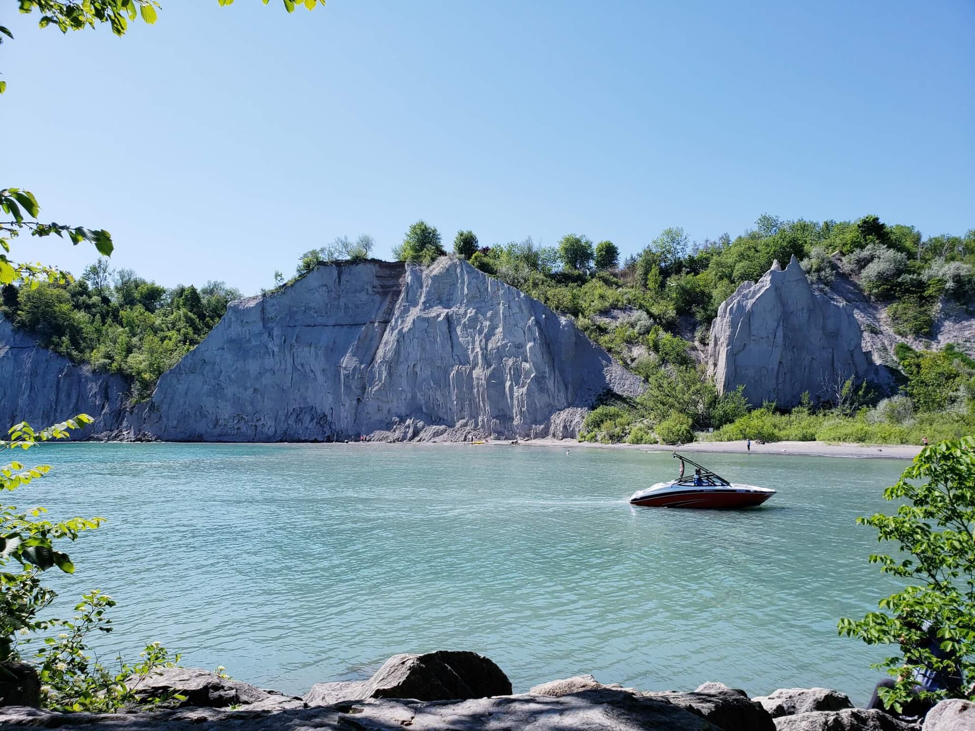 The white sandstone cliffs of the Scarborough Bluffs rising above the turquoise water at Bluffer's Park on Lake Ontario, with a boat on the calm bay