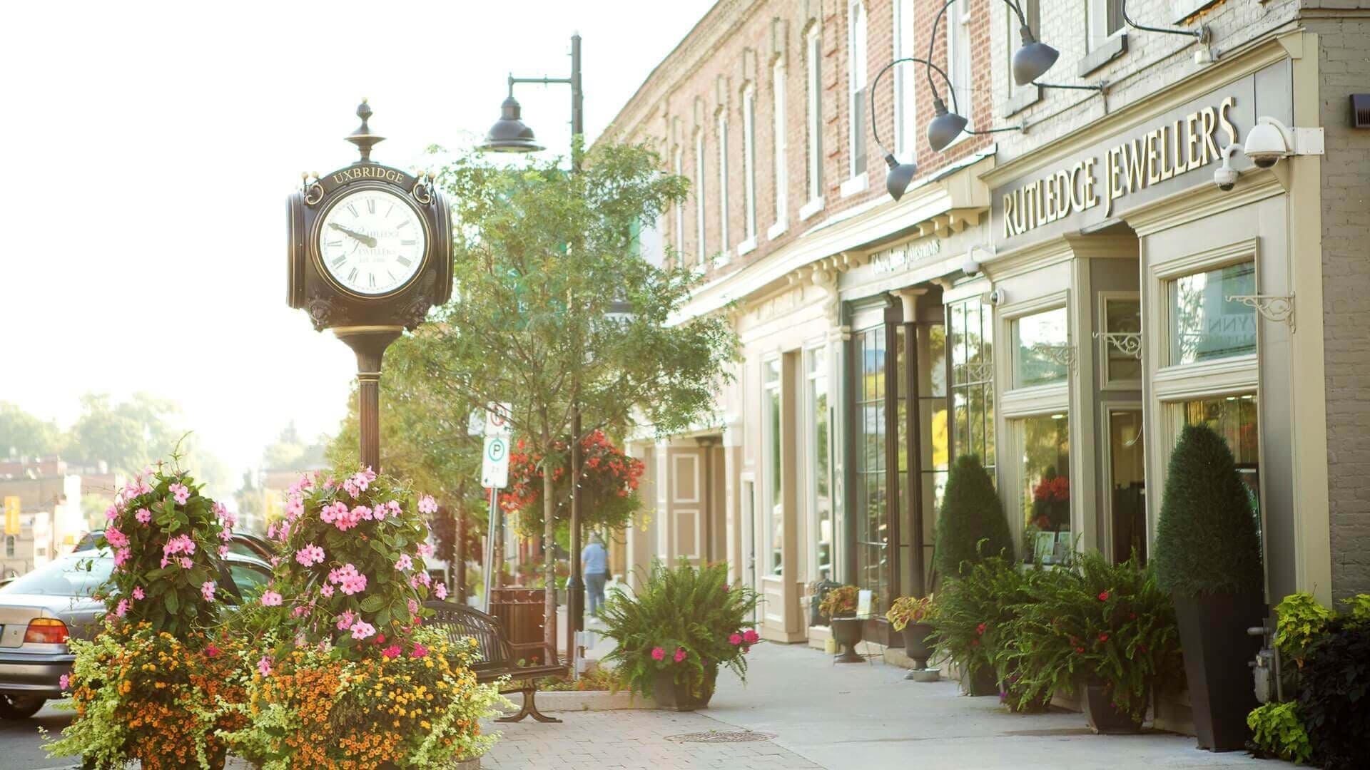 The Uxbridge street clock and flower planters outside heritage Brock Street storefronts in downtown Uxbridge, Ontario